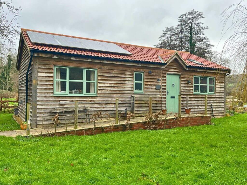 weathered oak cladding annexe with green door and windows